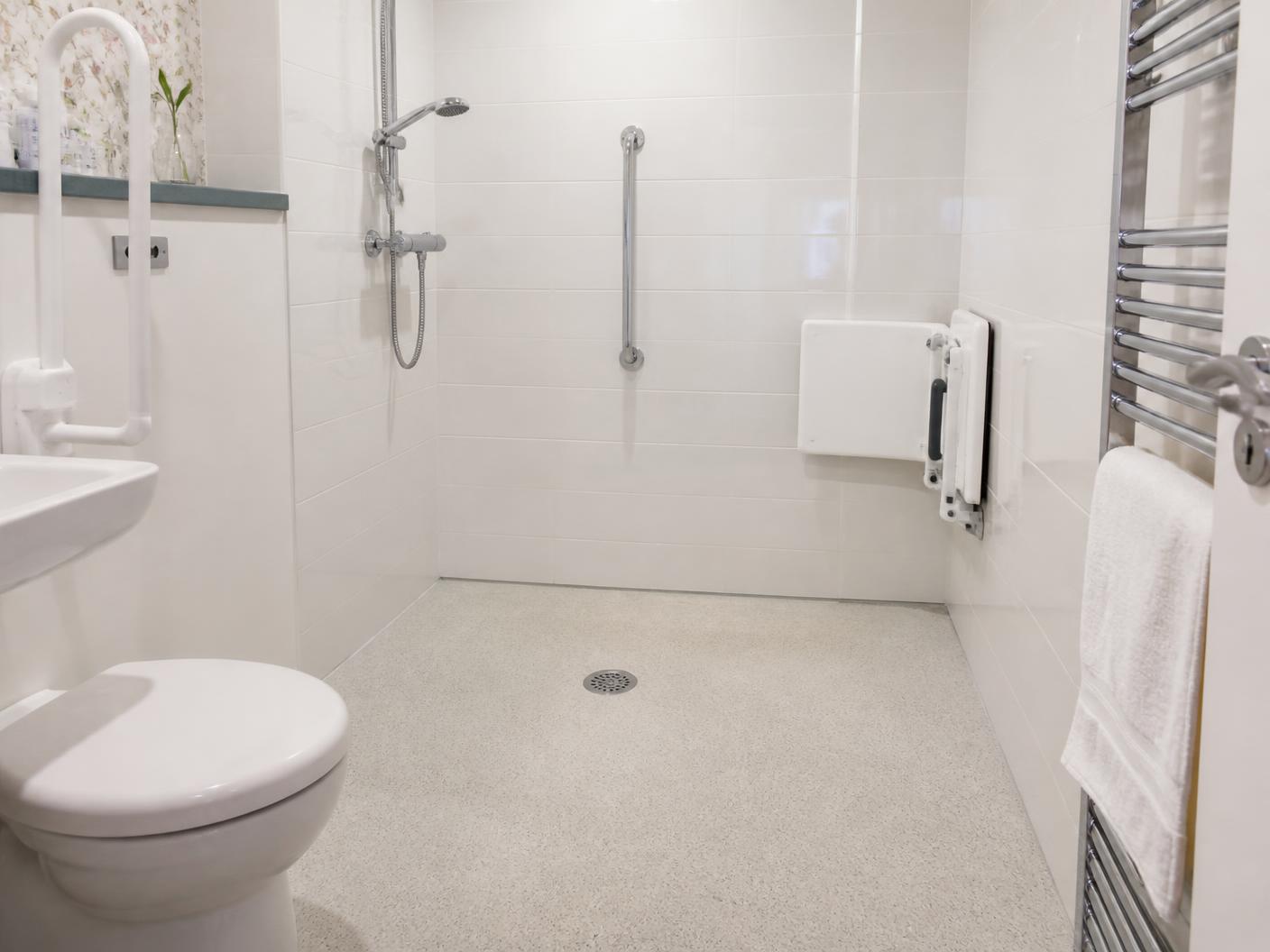 Level-access walk-in shower with grab rail and folding seat in a British bathroom
